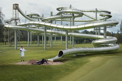 A big, gray slide with two people on the ground